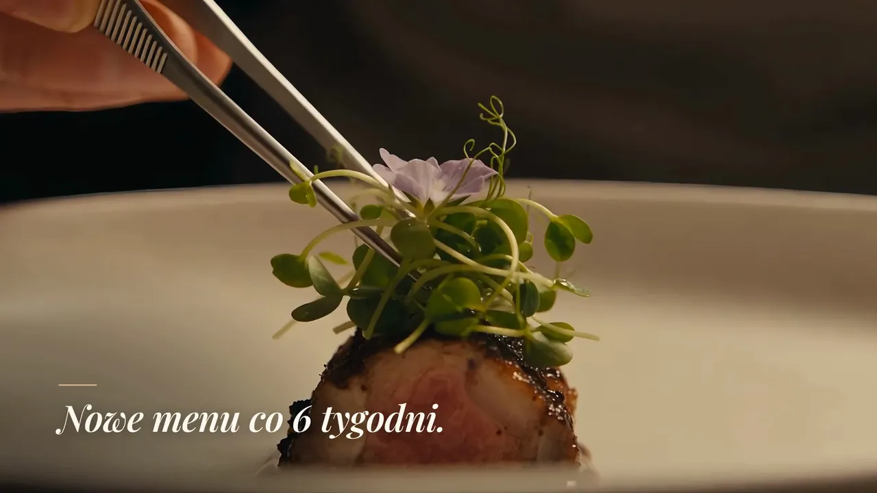 Film promocyjny restauracji: kucharz układa kiełki pęsetą i napis „Nowe menu co 6 tygodni.”